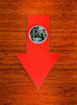 Red Arrow with Russian Ruble Down on the Wooden Background