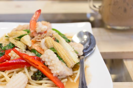 Spicy Spaghetti seafood in white dish on the wood table