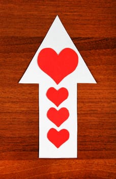 Red Heart Shapes on the Arrow and on the Wooden Background