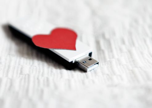 USB Flash Drive with Heart Shape on the White Fabric Background