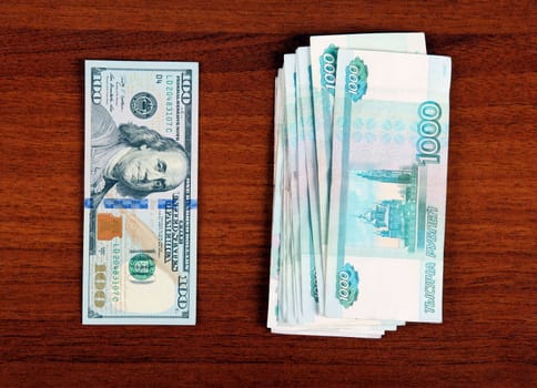Russian Roubles and American Dollars on the Wooden Background