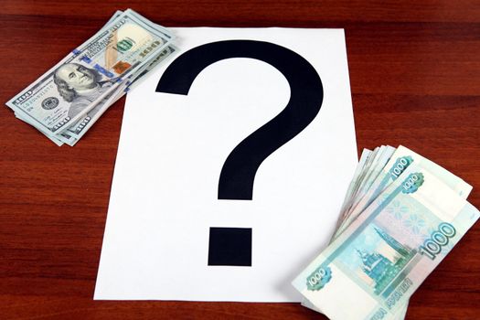 Russian Roubles and American Dollars with Question Mark on the Wooden Background