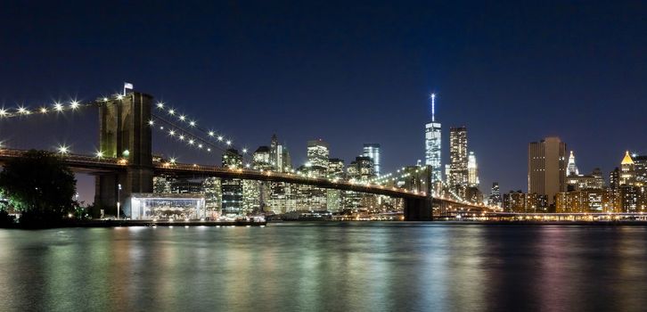 The New York City skyline at night w Brooklyn Bridge and Freedom tower