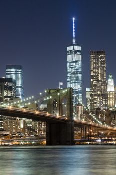 The New York City skyline at night w Brooklyn Bridge and Freedom tower