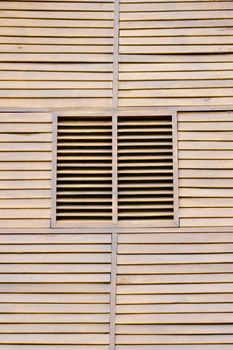 Closed wooden shutters on a wooden panneled wall.