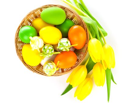 Basket with easter eggs and yellow tulips, on white background