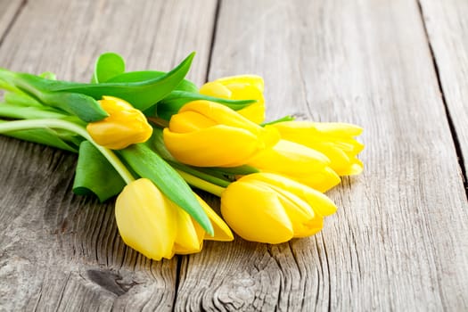 Bouquet of yellow tulips on old wooden boards