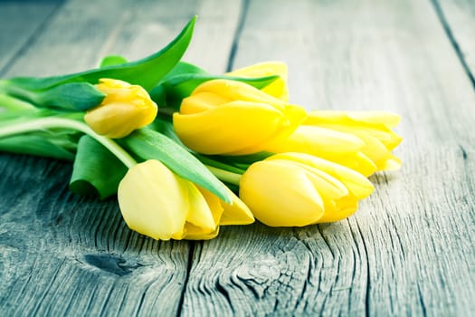 Bouquet of yellow tulips on old wooden boards