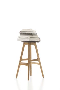 Conceptual Piled Books on Top of Tall Single Chair, with Wooden Legs, Isolated on White Background. Emphasizing Copy Space.