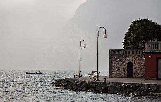 A man fishing near shore of the lake Garda in the northern Italy.