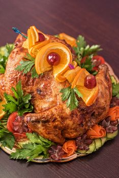Whole roasted chicken with vegetables and fruits on wooden table