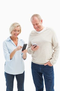 Happy mature couple using their smartphones on white background