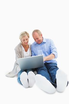 Happy mature couple using laptop on white background
