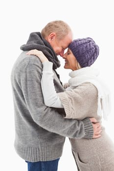 Happy mature couple in winter clothes embracing on white background