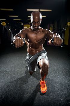 Muscular body builder working out  at the gym doing exercises on the cable machine.