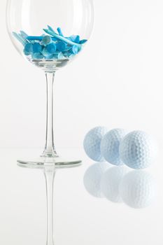 Glass of wine and golf equipments on the glass desk