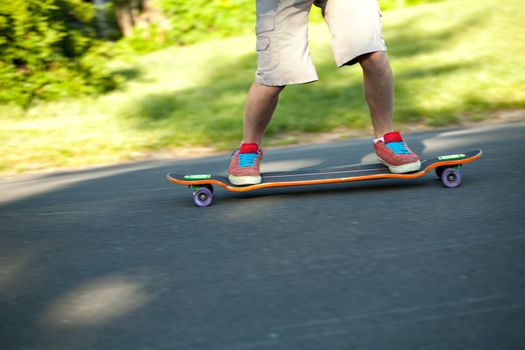 Action shot of a longboarder skating on a suburban road. Shallow depth of field. 