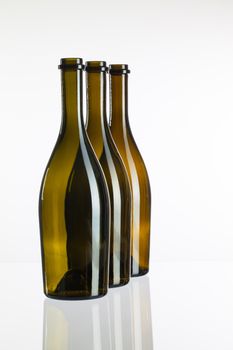 Three empty bottles of wine on a glass table