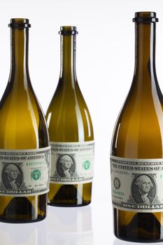 Empty bottles of wine from the label of dollar bill on a glass table