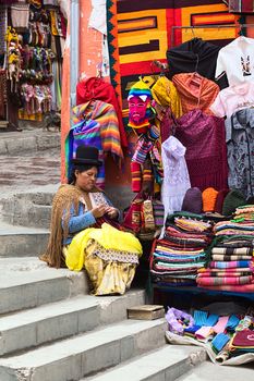 LA PAZ, BOLIVIA - NOVEMBER 10, 2014: Unidentified woman doing crochet sitting on the stairs beside her small street stand on the corner of the streets Sagarnaga and Linares in the city center on November 10, 2014 in La Paz, Bolivia