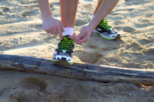 uomo in spiaggia che si allaccia le scarpe prima di un'attivit�� sportiva