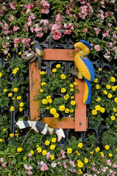 Summer background with old wooden plank, yellow and pink flowers and green leaves and birds.