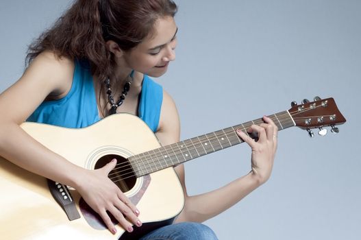 Pretty young woman playing her favorite songs on an acoustic guitar.