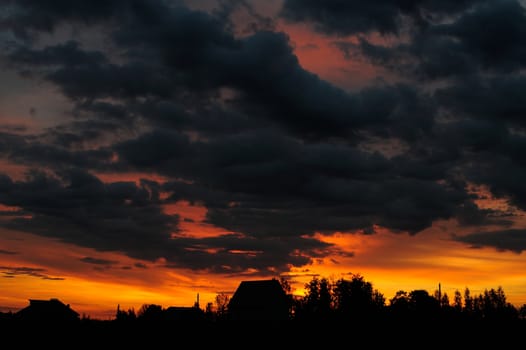 Dramatic sunrise with houses silhouette horizontal