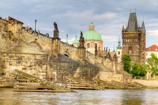 Photo shows the bridge, river and some old houses in Prague.