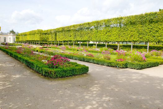 Photo shows French green garden with flowers and monuments.