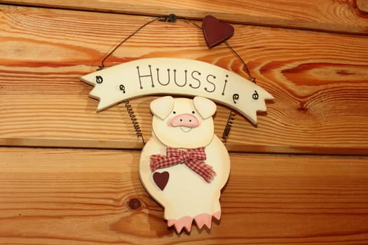 Decorative pink pig weighs on the wooden wall of the timber