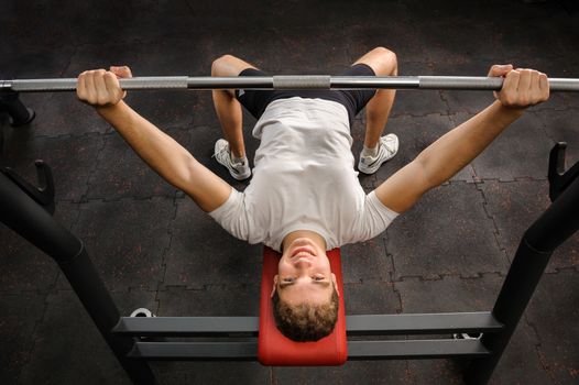 handsome young man doing bench press workout in gym