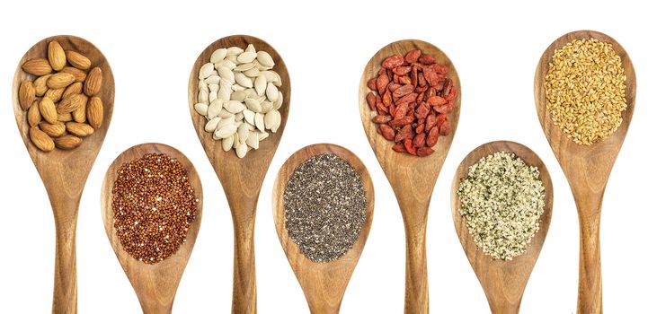 superfood abstract - isolated wooden spoons with almonds, red quinoa grain, pumpkin seeds, chia seeds, goji berry, hemp seed hearts, and golden flax seed