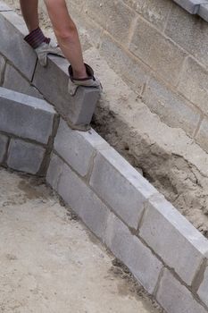 Putting bricks on a constructed wall outdoors