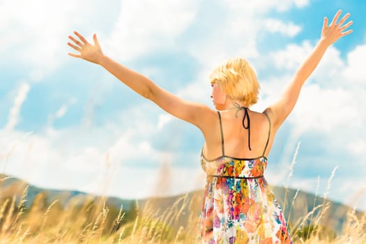 A portrait of a casual dressed beautiful young Caucasian woman outdoor in the meadow on a sunny summer day.