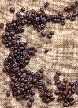 Heap of burnt brown coffee beans on sackcloth background