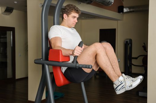 Handsome young man doing lats pull-down workout in gym