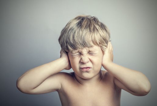 boy with closed ears on a gray background