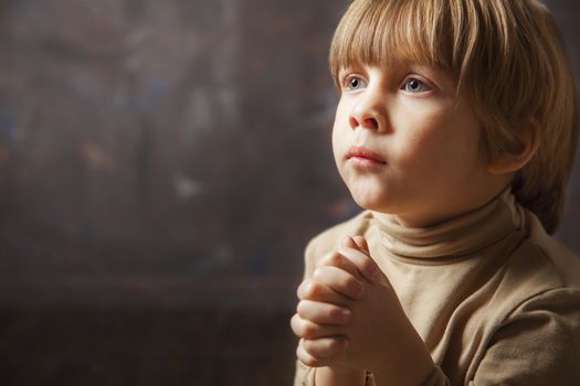 Little young beautiful boy spiritual peaceful praying and wishing, horizontal, copy space.