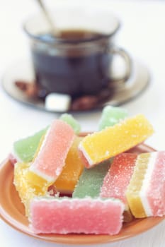 fruit jellies are in a saucer, near a cup with tea