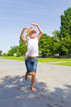 Cute girl with blond hair jumping on one leg