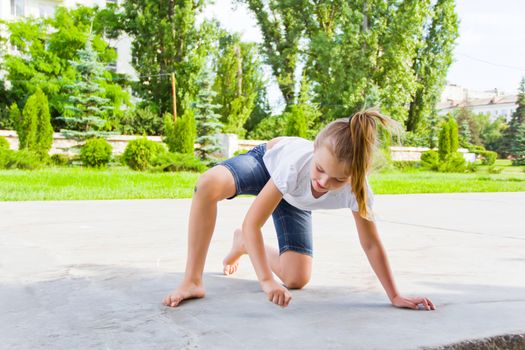 Cute girl draws chalk on asphalt in summer