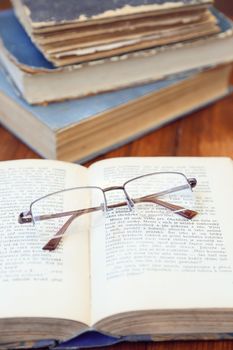 glasses lie on a few opened age-old books