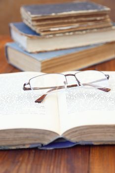 glasses lie on a few opened age-old books