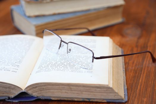 glasses lie on a few opened age-old books