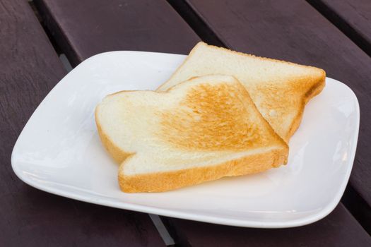 two toasts in white dish on brown table