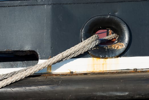Detail of the ropes of a black tugboat with rust