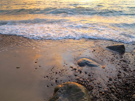 The waterfront. Rocks, water and wet sand