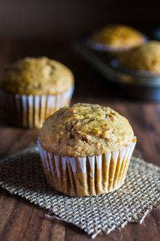 Applesauce carrot muffins on a wooden table with the afternoon sun shinning in.