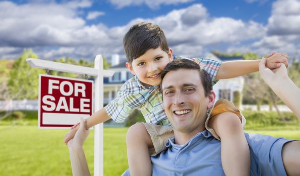 Mixed Race Father and Son Celebrating with a Piggyback in Front Their House and For Sale Real Estate Sign.